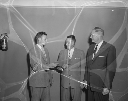 College of Education Professor Blackstone and an unidentified man award top graduate Keith McPhee.