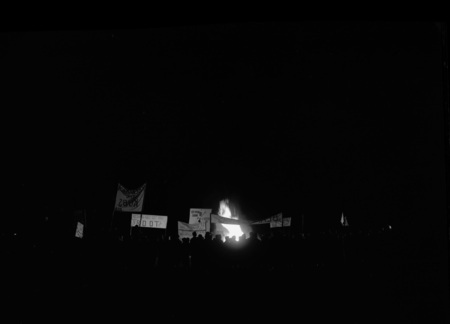 Students gather at Homecoming bonfire and rally with signs and banners.