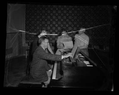 School of Music Faculty member Glen Lockery at the piano with several members of the Vandaleers.