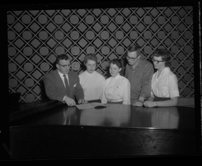 Glen Lockery, School of Music faculty, standing with members of the Vandaleers at a piano.