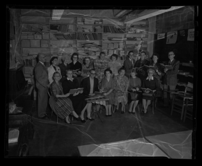 A music teachers meeting with facuty reading from a book titled "New Music Horizons".