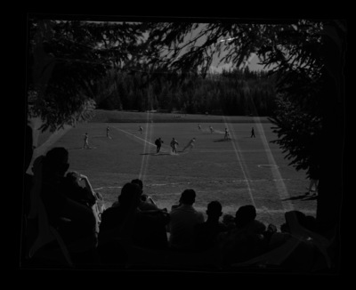 A photograph from behind a small crowd at a baseball game.