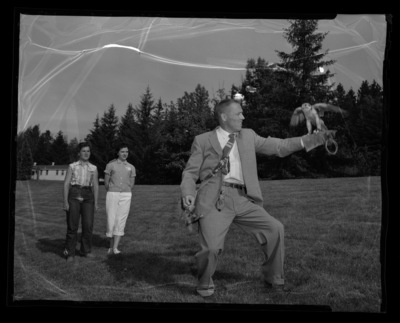 Morlan Nelson, conservationist and falconer, showing falcons to 4-H members, pictured behind Nelson, in an MacLean Field.