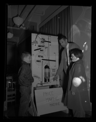 University of Idaho graduate student, John Ensunsa, showing a price making machine to two young future farmers.