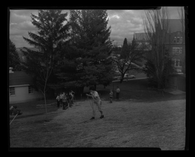 Students in ski class practice going downhill on skis without snow in a grassy hill behind the Radio-TV Building just south of the Administration Building. The Administration Building can be seen in the background.