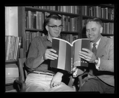 Business Administration Department Professor Paul Groke with student reading an economics textbook.