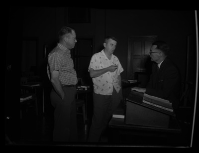 Three men having a coversation in a classroom for the annual Public Utilities Executive course.