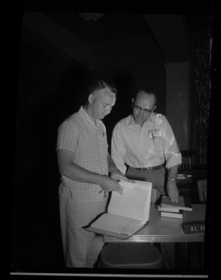 Two men read a book together for the annual Public Utilities Executive course held each summer.