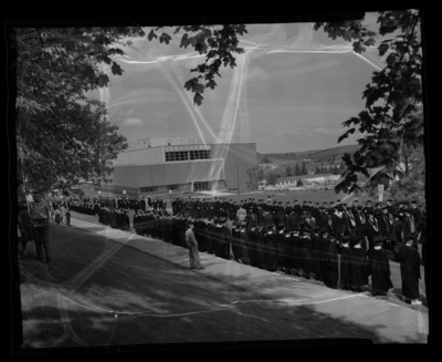 The Academic Parade leads the traditional commencement walk from the Administration Building to Memorial Gym. The Library building can be seen in the background.