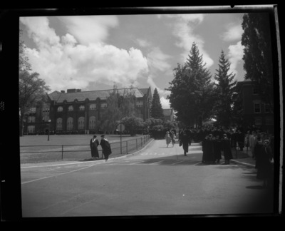 Students in cap and gown outside of the Administration Building on commencement day.