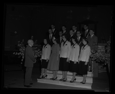 President Theophilus congratulates the top 15 seniors at the annual May Fete event in Memorial Gym. Individuals identified as listed. Front: Ann Marie Becker, Edith Louise Vandenbark, Neela McCowan, Patricia Kay Bozarth, Carolyn Dempsey Mitchell; middle: Dwight Chapin, Leo Tafolla, Karl Bittenbender, Jack Macki, James Flanigan; back: Bruce Summers, Terence White, William Agee, Roland R. Lodge. Not pictured, Laird Noah.