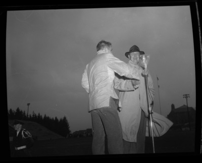 Dick Kerbs, left, shakes hands with an unidentified honoree on stage during the 1957 homecoming game.