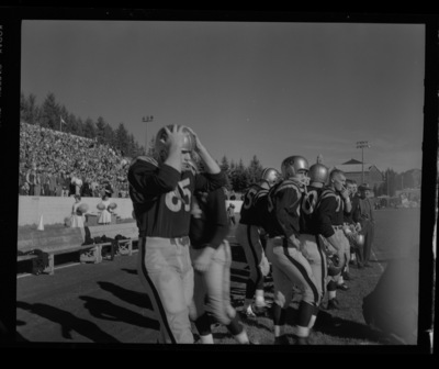 Football players get ready to play at the sidelines.