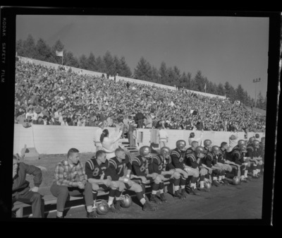 Football players sit at the sidelines at the Homecoming game.