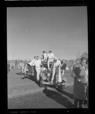 Members of the cheer and yell squads riding on a vehicle on the football field after the Homecoming game.