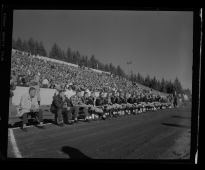 Football players sit at the sidelines at the Homecoming game.