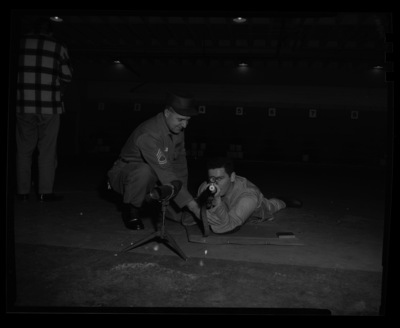 ROTC student learning to shoot a rifle at the rifle range with help of an instructor.