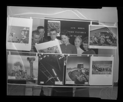 Students looking at news pictures of the year display in library.