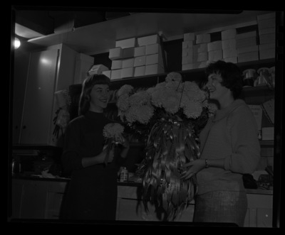 Two members of the Morter Board with Homecoming  "I" mums bouquet.