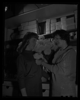 Two members of the Morter Board with Homecoming  "I" mums bouquet.