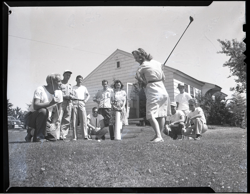 A group of golfers tees off just outside of the clubhouse.
