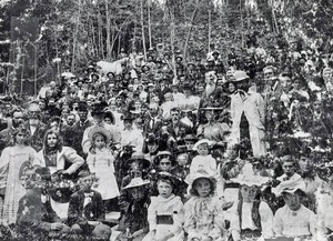 Photo of a [l]arge group of people sitting in the woods