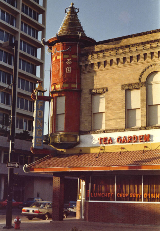 A city-scene showing Fong's Chinese Restaurant and the Tea Garden building in Old China Town, Boise, Idaho, was entered into the Boise Camera Club competition and received a score of 21. On the corner of the building is a neon blade sign and a neon sign above the eave. 