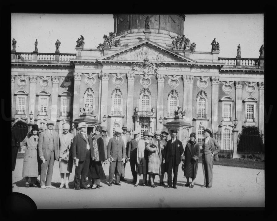 A group of people gather for a portrait in front of a building in an unknown location.