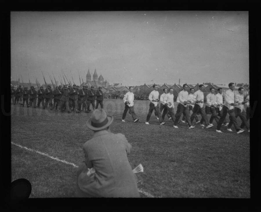 A military parade in an open field, with infantry and gunmen in foreground.