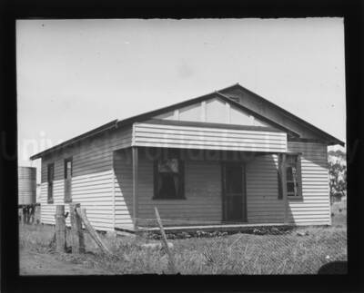 House with water tank at the back. A wire fence surrounds the building.