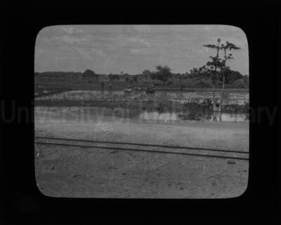 A distance view of a rural scene, with men working in fields.