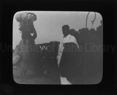 An unidentified man poses alongside another man holding luggage.