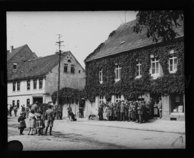Group of people posing for a portrait in front of a building observed by children and passersby.
