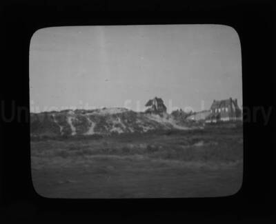 Two houses stand on a sandbar in the distance.