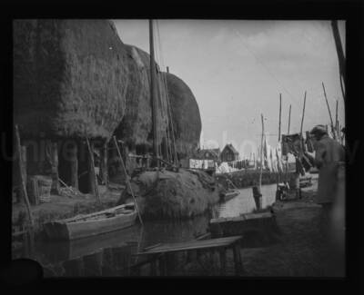 Thatched-roof huts along the shore of a canal.
