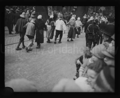 People in a costume parade on an unidentified street.