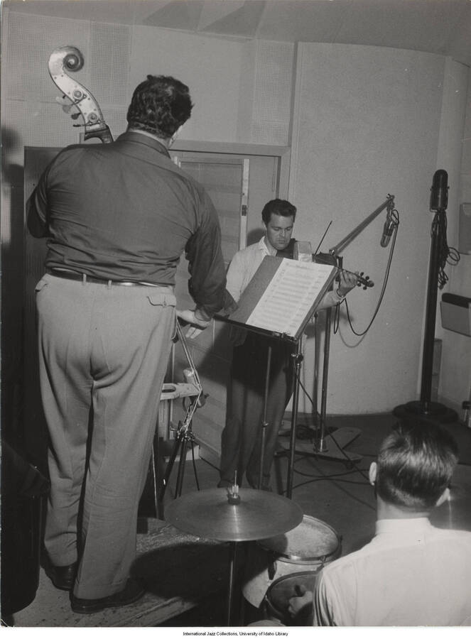 9 1/2 x 7 inch photograph; unidentified  bassist and drummer and violinist Svend Asmussen are performing in a studio