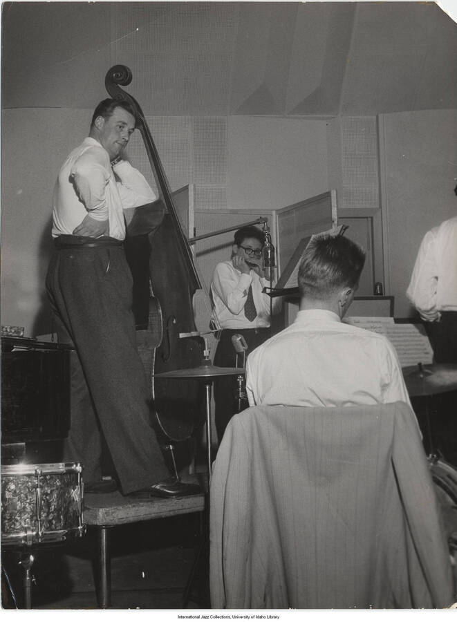 9 1/2 x 7 inch photograph; unidentified bassist, harmonicist, and drummer, performing in a studio