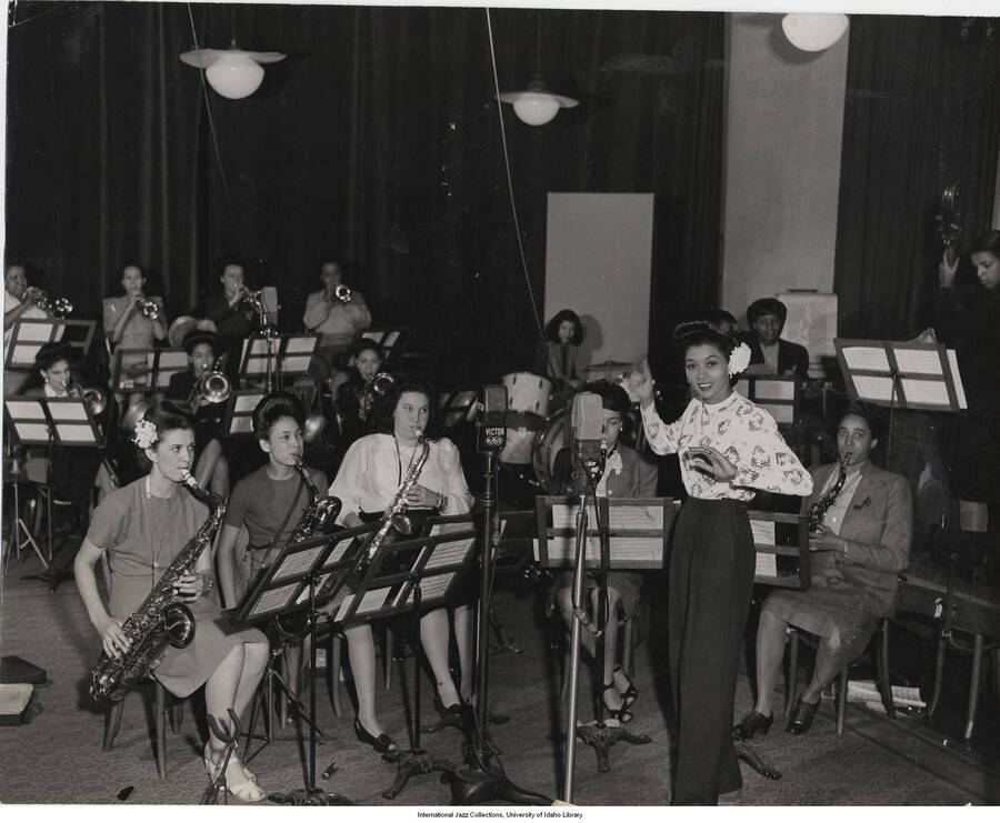 7 5/8 x 9 5/8 inch photograph; Sweethearts of Rhythm at RCA. Anne Mae Winburn, conducting, with Vi Burnside behind. This photograph is published in Leonard Feather's book The Jazz Years: Earwitness to an era