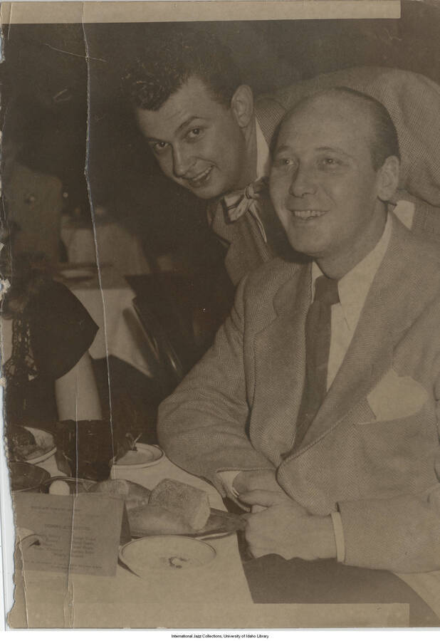 5 x 3 1/2 inch photograph; man seated on the right, in the restaurant, is vibraphone, xylophone and band leader Kenneth "Red" Norvo.