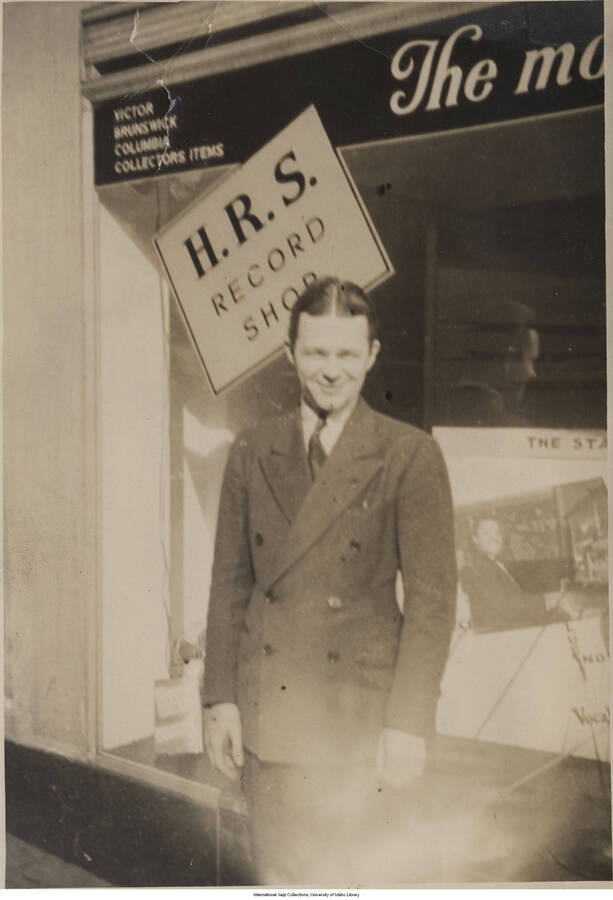 6 3/4 x 4 3/4 inch photograph; unidentified man standing in front of a store window with a sign that reads: H.R.S. Record shop