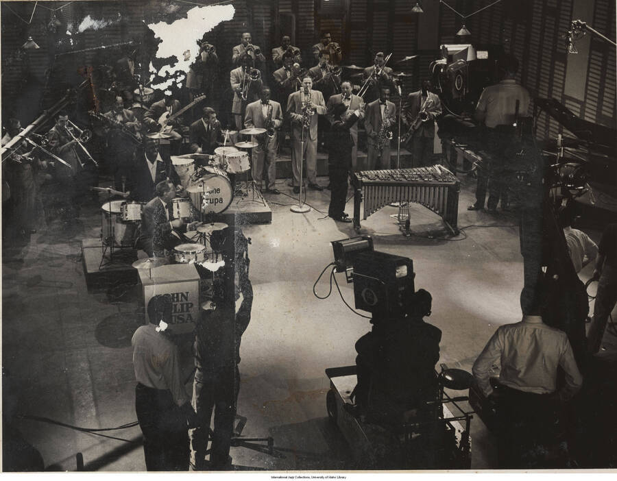 9 x 7 inch photograph; Gene Krupa performing with unidentified musicians. Handwritten on the back of the photograph: CBS Timex