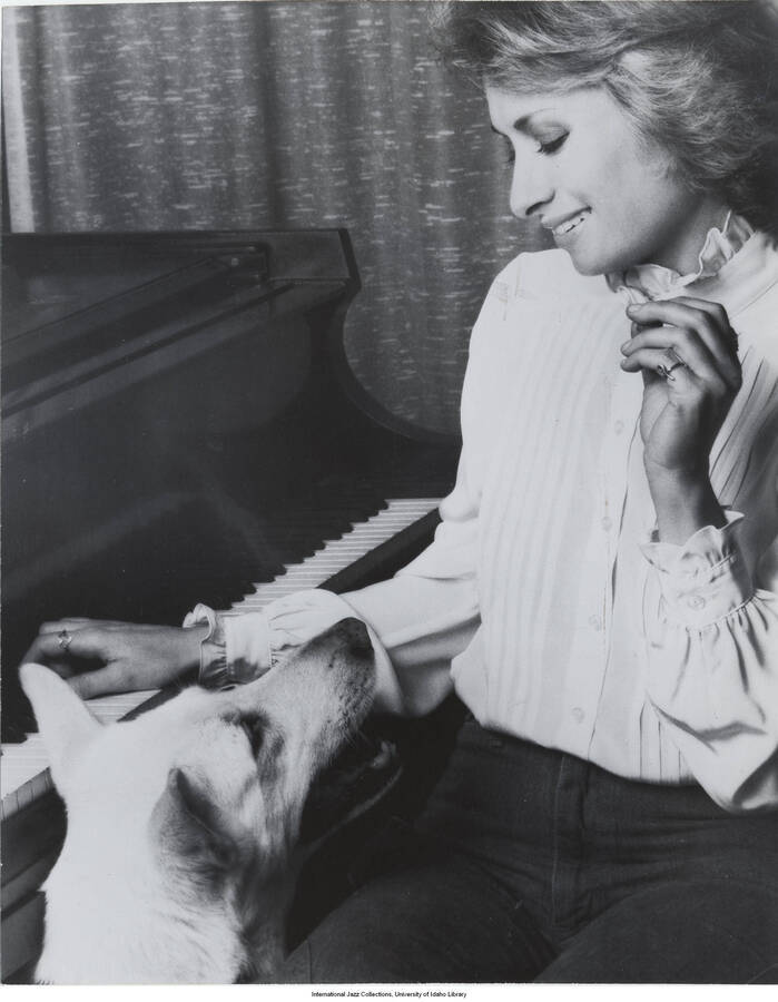 10 x 8 inch photograph; Joanne Grauer by the piano with a dog
