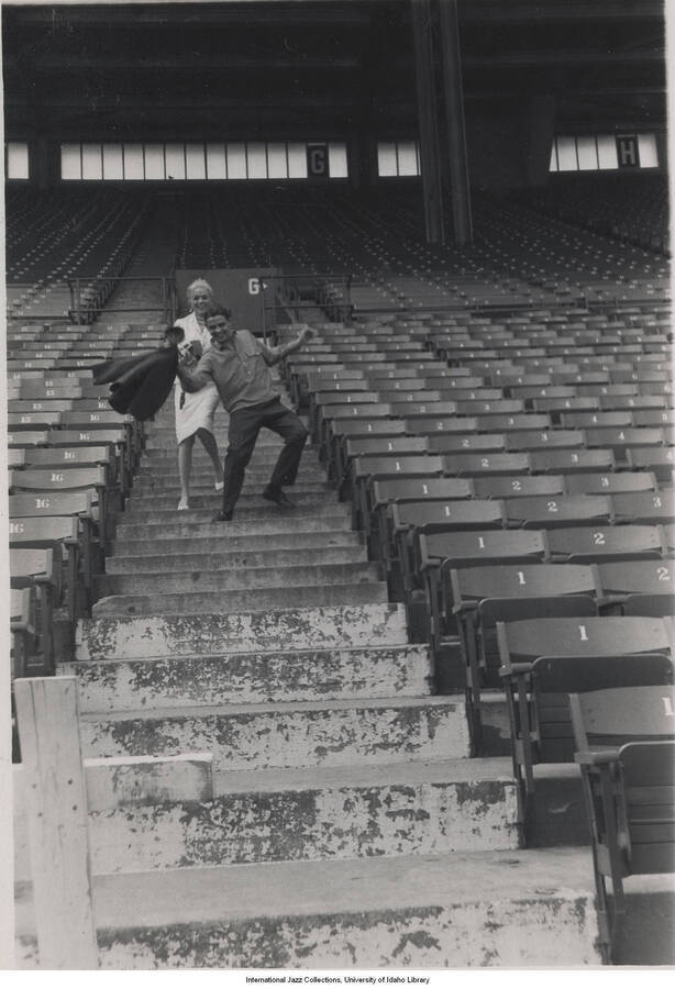 5 x 3 1/2 inch photograph; unidentified press photographer and man, climbing down the steps of a stadium