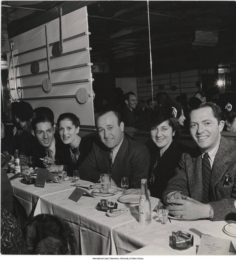 8 x 7 1/2 inch photograph; Leonard Feather with unidentified men and women, in a restaurant. Stamped on the back of the photograph: Reproduction not permitted. LIFE Magazine; David O. Alber, NY