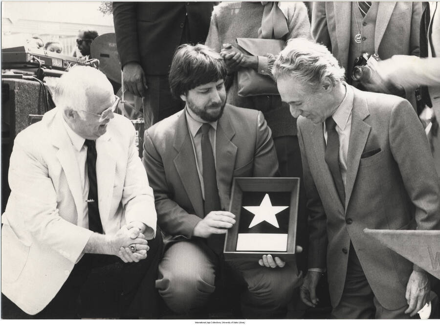 5 x 7 inch photograph; Leonard Feather and two unidentified men, one of whom is holding a plaque