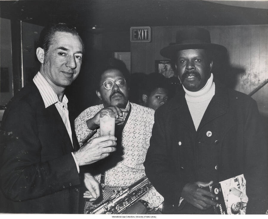 8 x 10 inch photograph; Leonard Feather with unidentified saxophonist and man, holding a LP album with the picture of the saxophonist on the cover