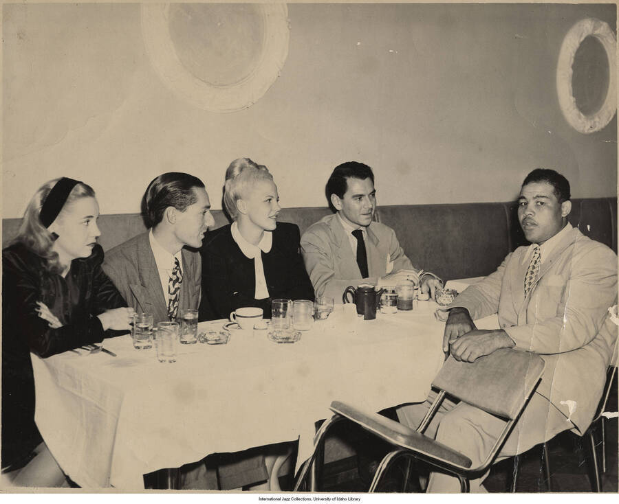 8 x 10 inch photograph; Leonard Feather with Peggy Lee, Dave Barbour, and Joe Lewis, in a restaurant