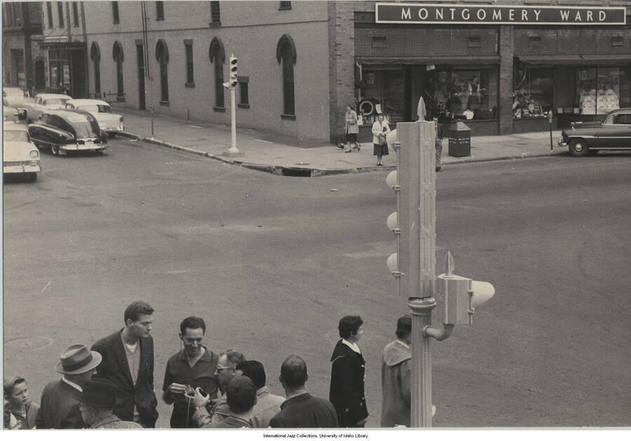 6 1/2 x 9 1/2 inch photograph; Leonard Feather and unidentified persons on a street. Observable in the background is the Montgomery Ward department store