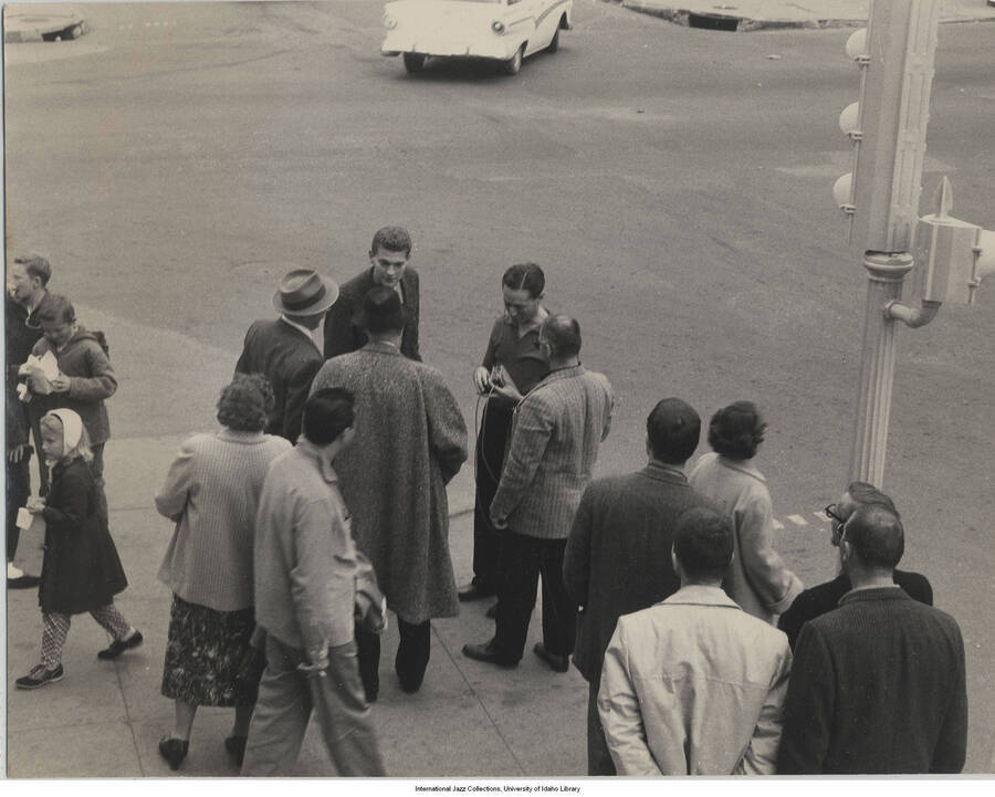 7 1/2 x 9 1/2 inch photograph; Leonard Feather and unidentified persons on a street